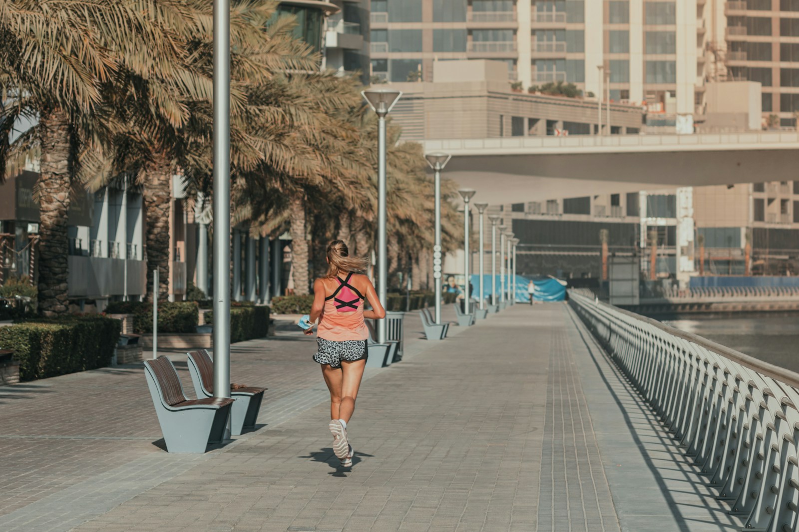 A woman walking down a sidewalk next to a body of water